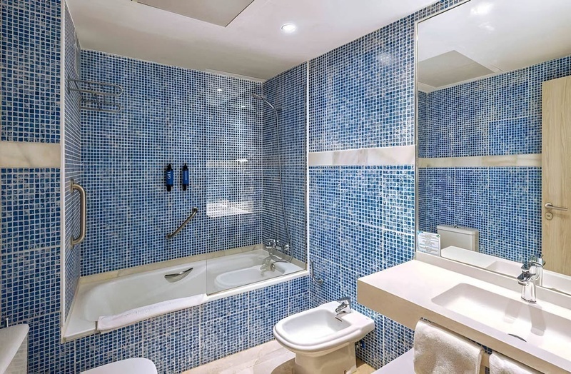 a bathroom with blue tiles and a bidet