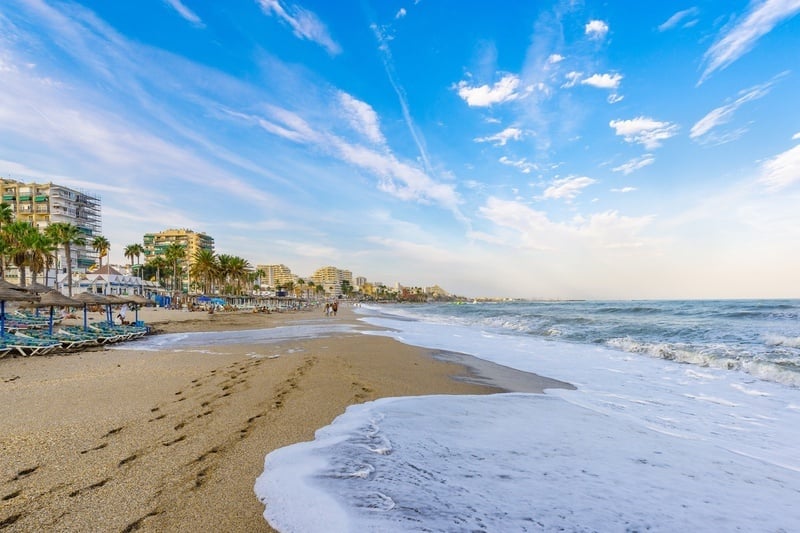 une plage avec des parasols et des bâtiments en arrière-plan