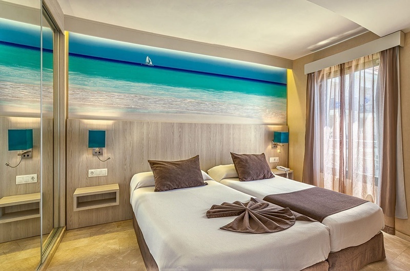 een hotelkamer met twee bedden en een schilderij van de oceaan aan de muur