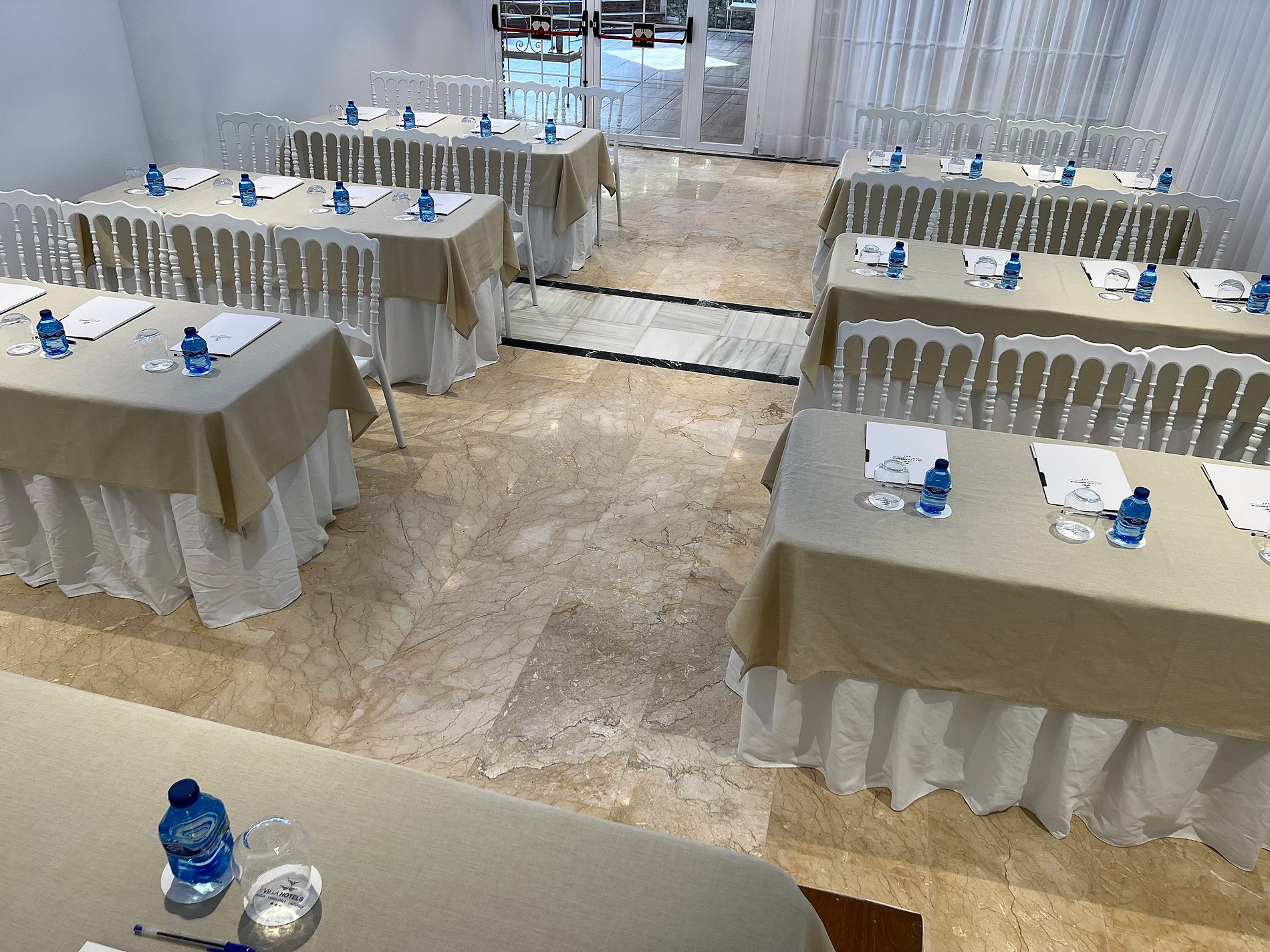 Salón de eventos preparado con mesas, sillas y agua para eventos | Villa Flamenca | Beneste Hoteles | Web oficial