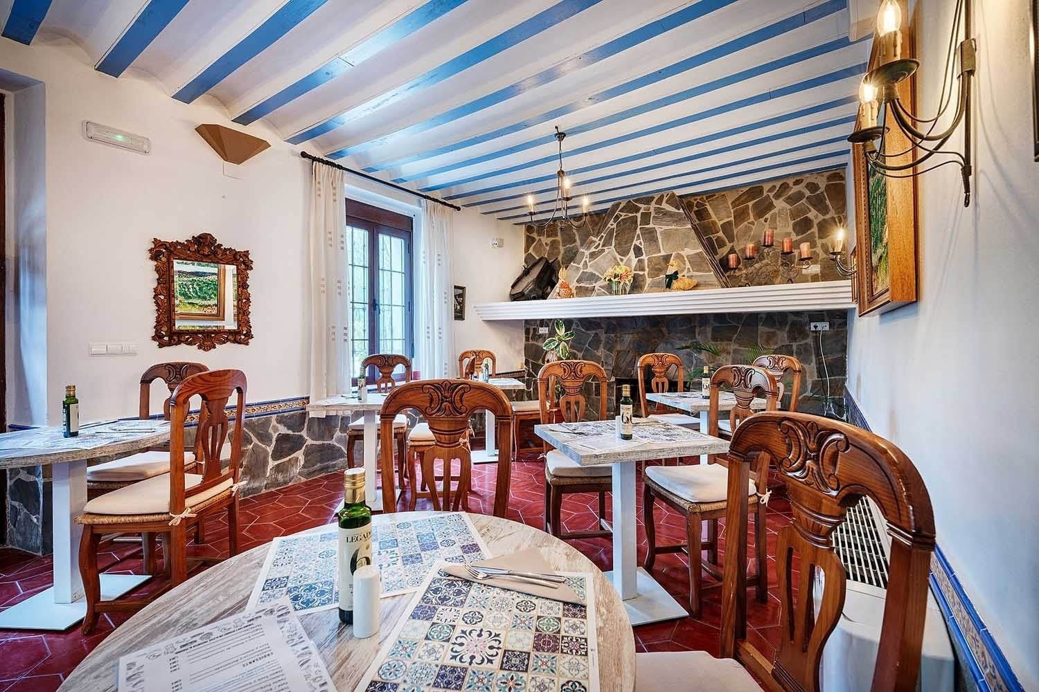 Comedor de Cazorla Hotel | Beneste Hoteles | Web oficial, con mesas y sillas de madera junto a chimenea de piedra.