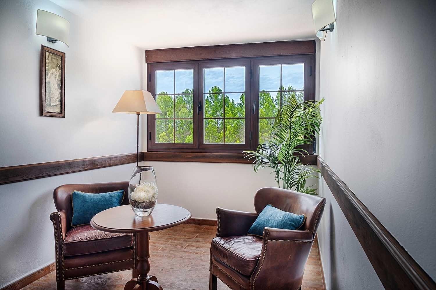 Rincón acogedor con sillones de cuero y ventana a la naturaleza en Cazorla Hotel | Beneste Hoteles | Web oficial.