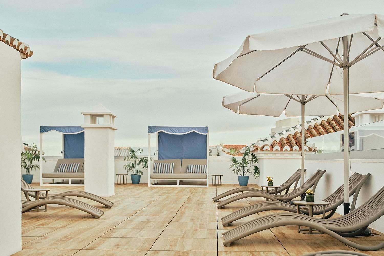Relájate en la terraza de Villa Flamenca | Beneste Hoteles. Tumbonas y sombrillas esperándote.