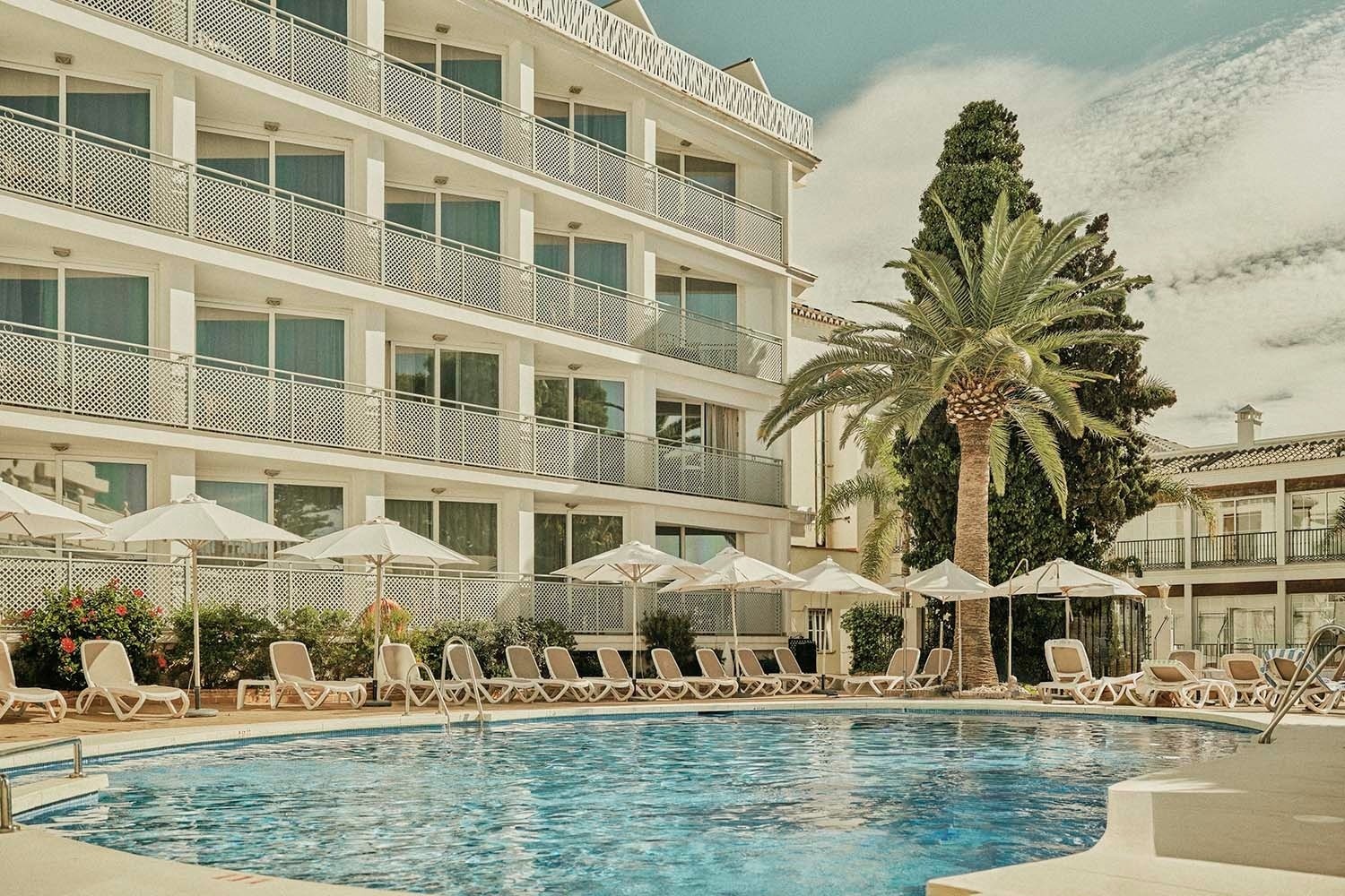 una piscina con palmeras y edificios en el fondo