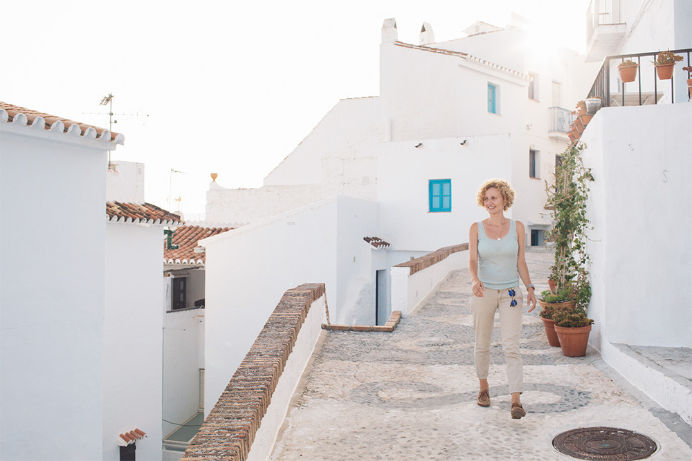Mujer paseando por calle blanca deBENESTE: Corporativa mediterráneo.
