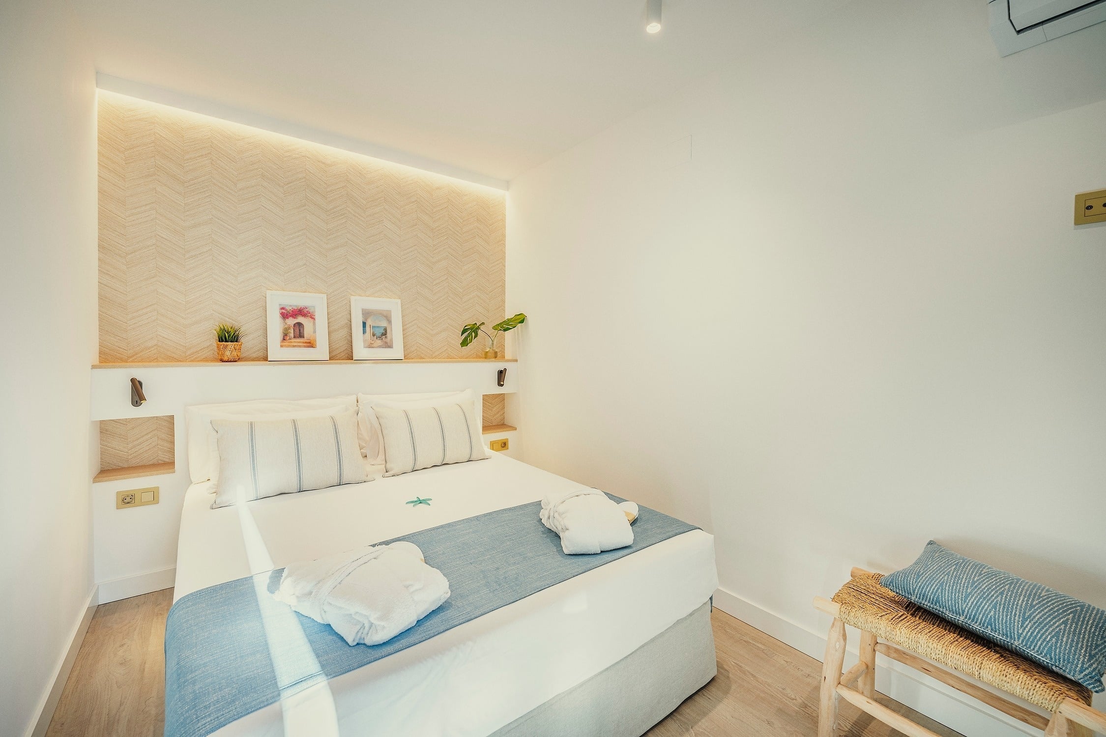 Un dormitorio moderno y luminoso con una cama hecha y decoración minimalista en tonos claros.