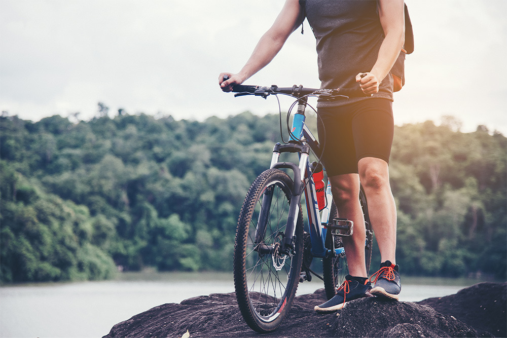 Ciclista en BENESTE: Corporativa con vistas a un lago y montañas boscosas