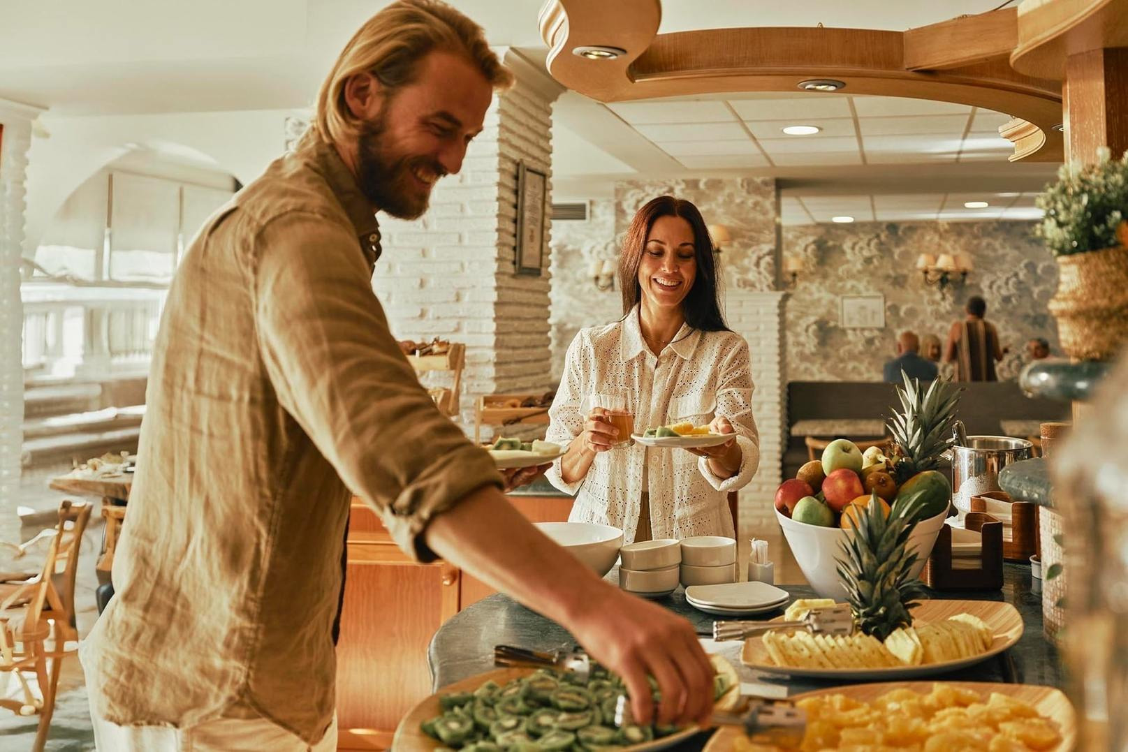 Desayuno Buffet | Villa Flamenca | Beneste Hoteles | Web oficial: Pareja sonríe disfrutando del buffet de desayuno.