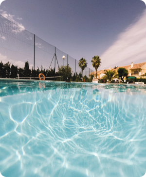 una piscina con palmeras y edificios en el fondo