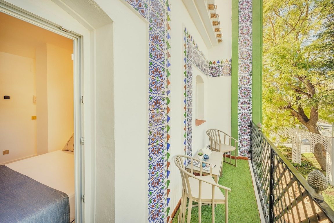 BENESTE: Balcón con azulejos, sillas y mesa, ideal para estancias corporativas.