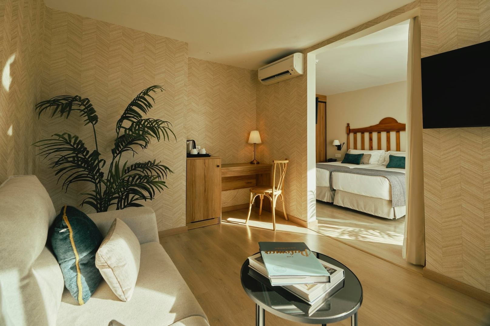 BENESTE: Corporativa modern hotel room with sitting area, desk, and double bed.
