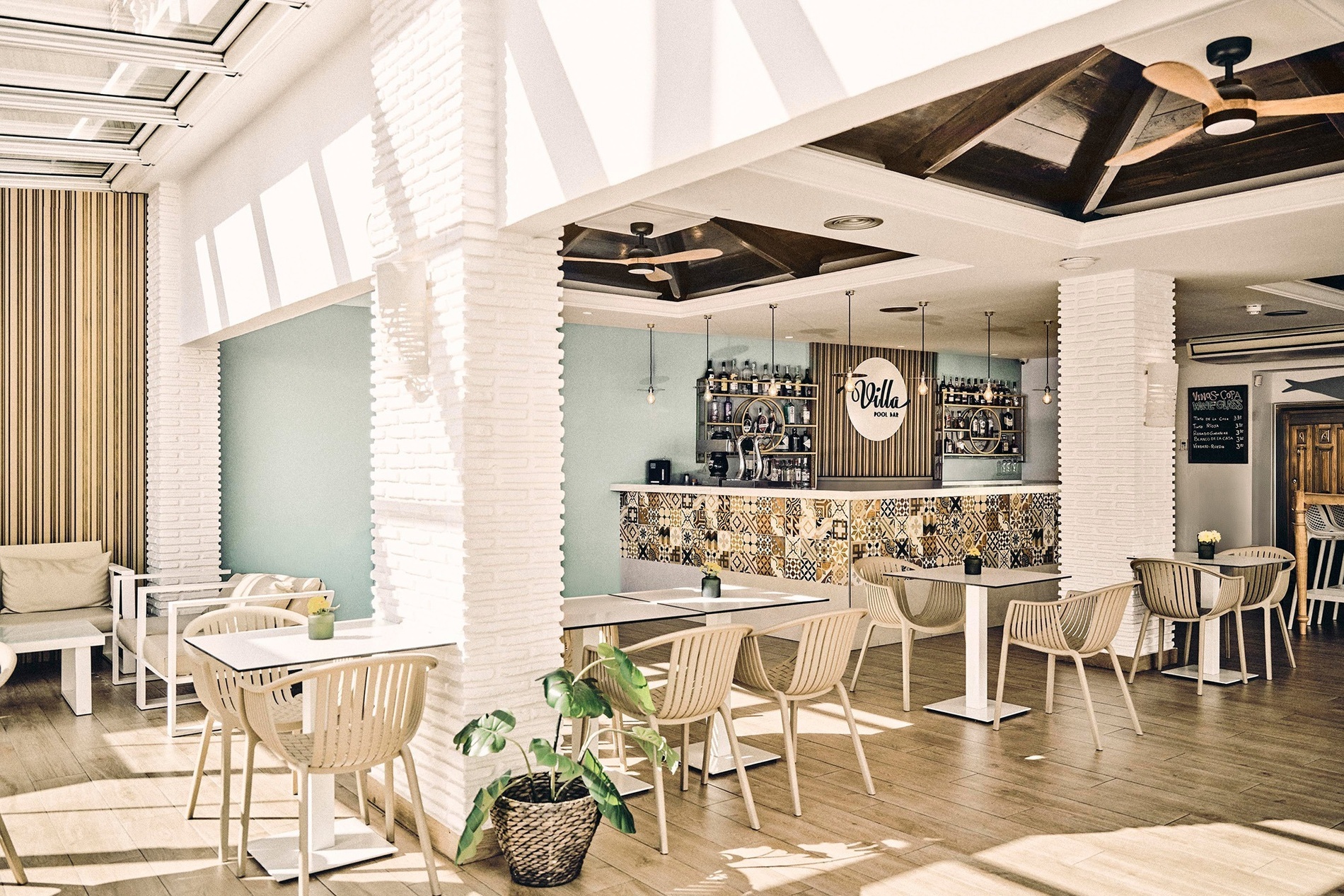 Interior de un acogedor bar o restaurante con mesas y sillas de madera, una barra de bar y una chimenea de ladrillo.