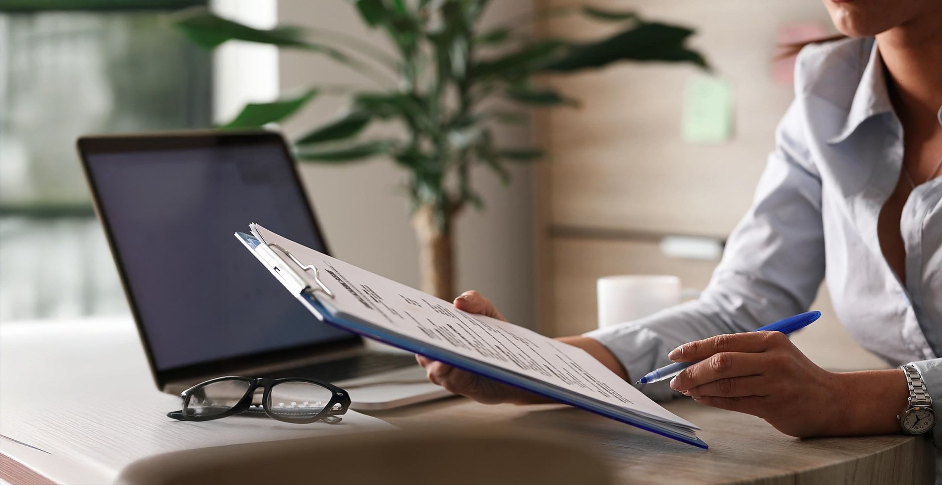 BENESTE: Corporate, woman reviewing documents with laptop and glasses.
