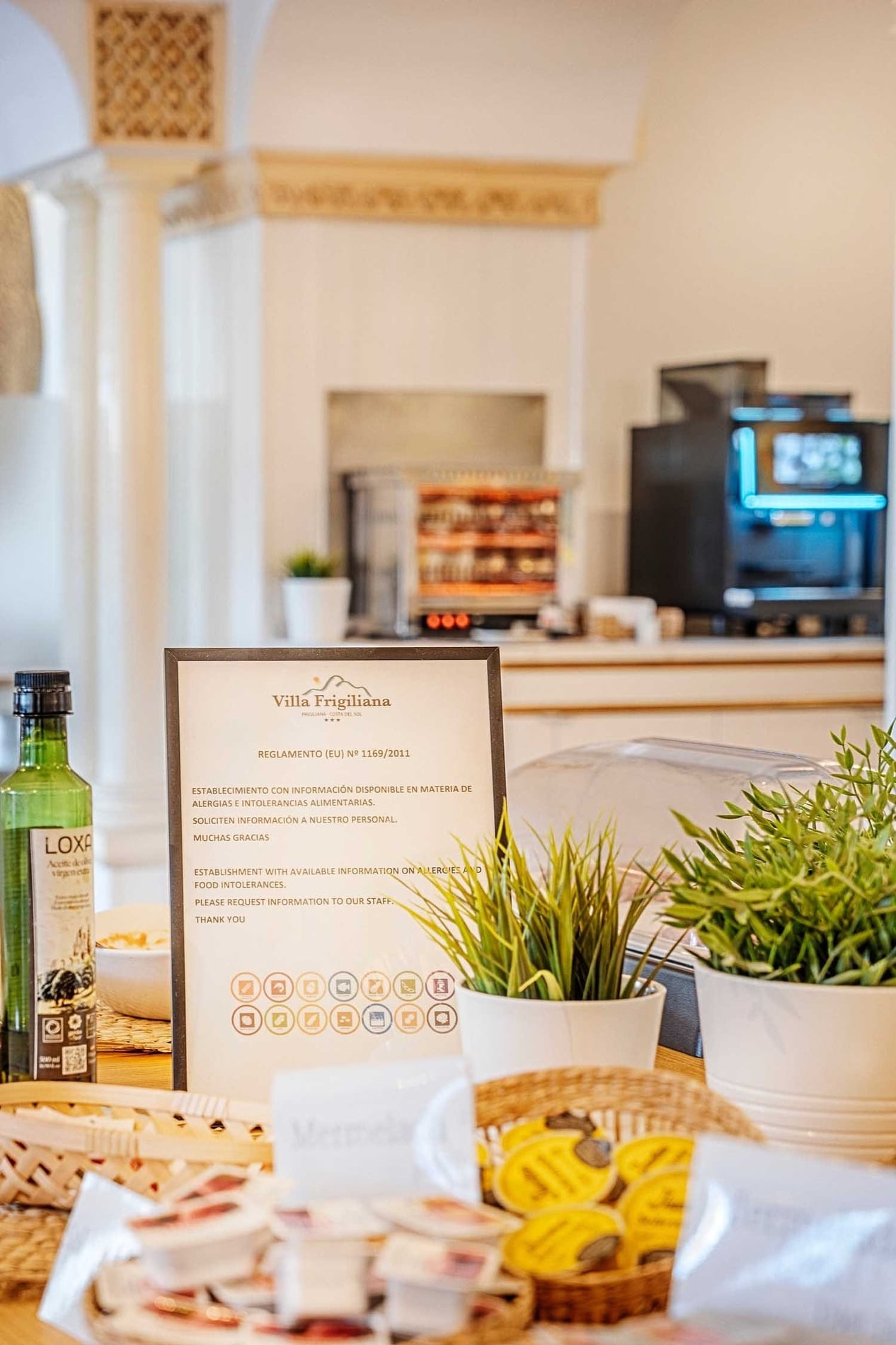 Hotel Frigiliana: Mesa de desayuno con aceite, hierbas y cartel informativo sobre alérgenos. ¡Reserva ya en Beneste Hoteles!