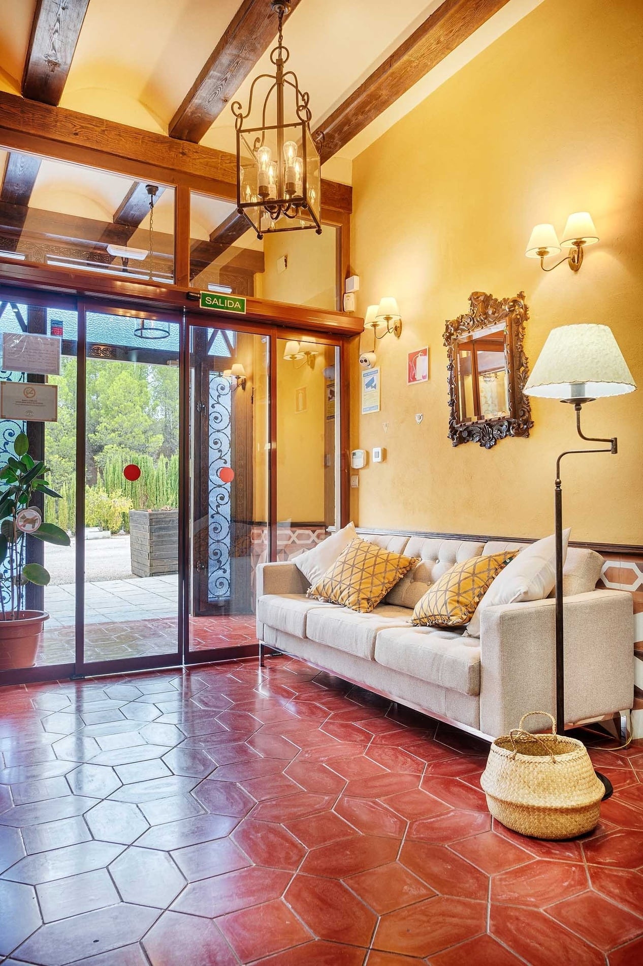 Salón acogedor de Cazorla Hotel | Beneste Hoteles, con sofá, lámpara y suelo de terracota.