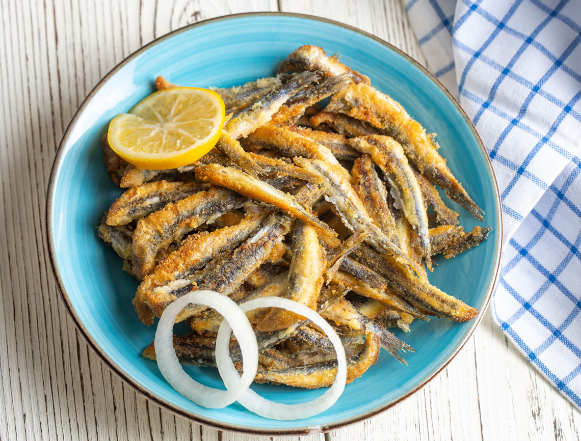 Pescado frito en el plato, servido con limón y cebolla. BENESTE: Corporativa