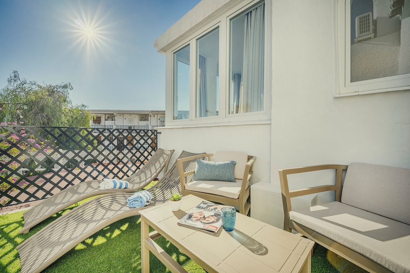 Balcón BENESTE: Corporativa con tumbonas, sillón y mesa, ideal para relajarse al sol.