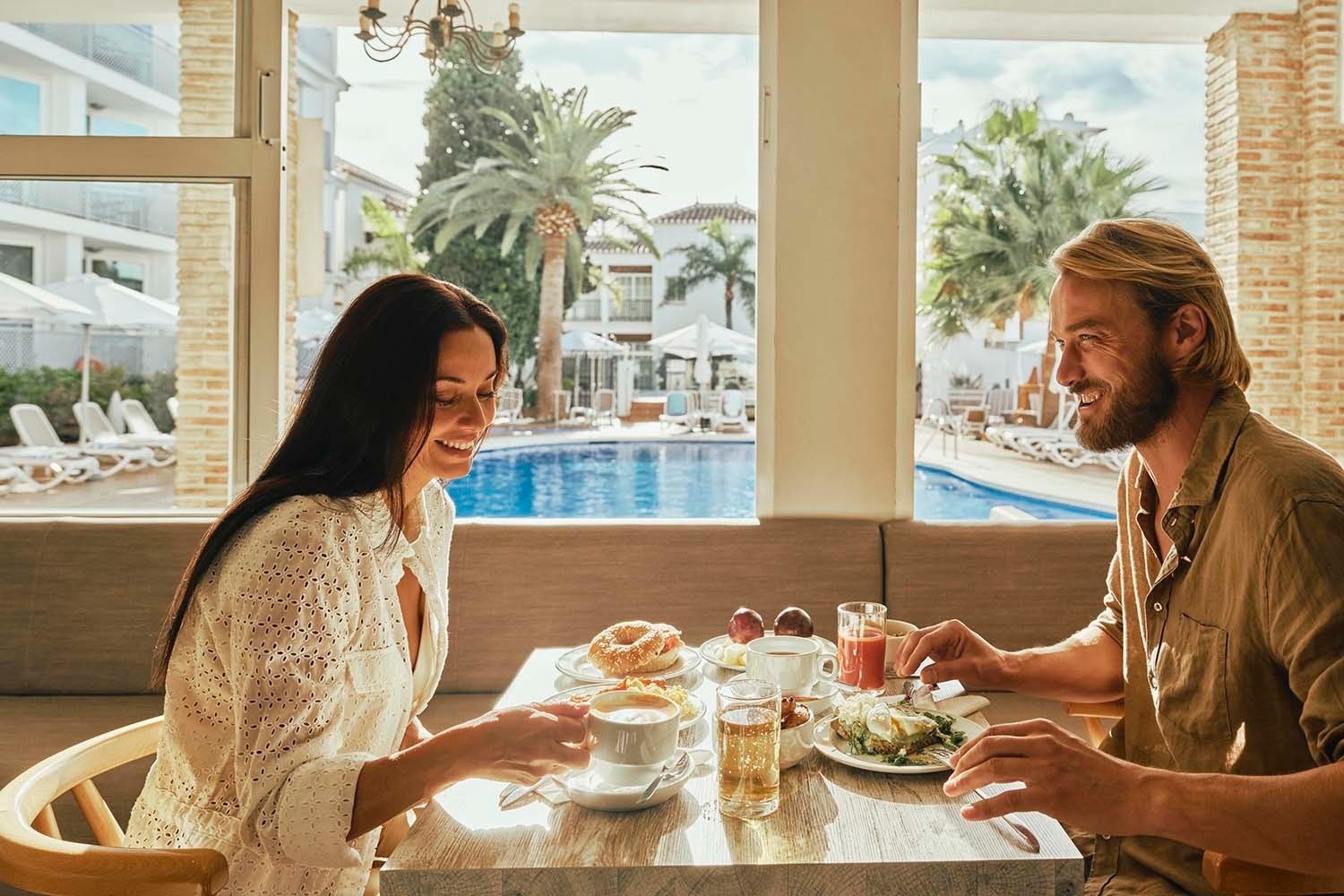 Pareja disfrutando de desayuno junto a la piscina. Gastronomía | Villa Flamenca | Beneste Hoteles | Web oficial.