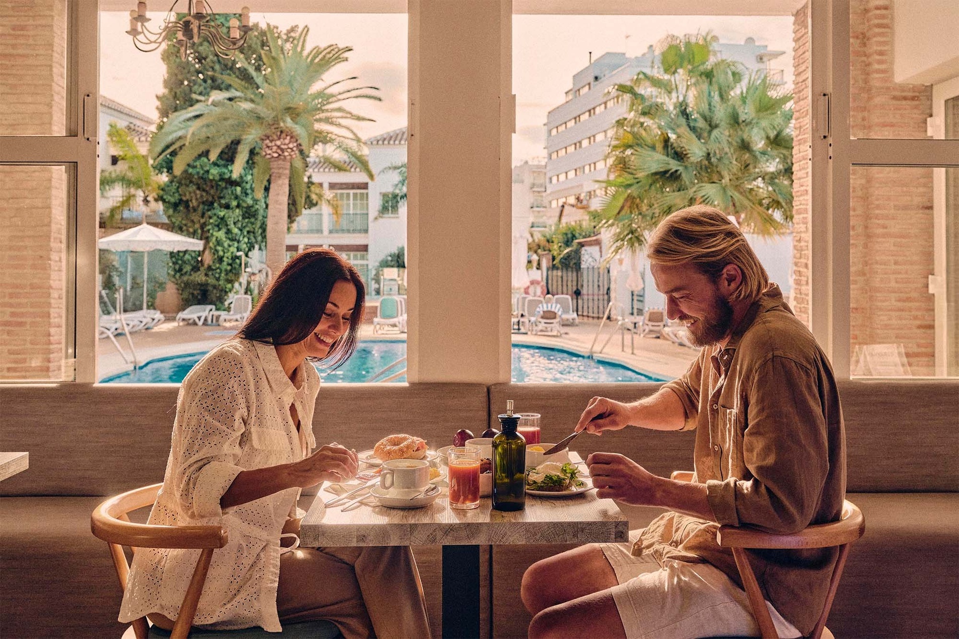 Couple enjoying breakfast at BENESTE: Corporativa resort by the pool.