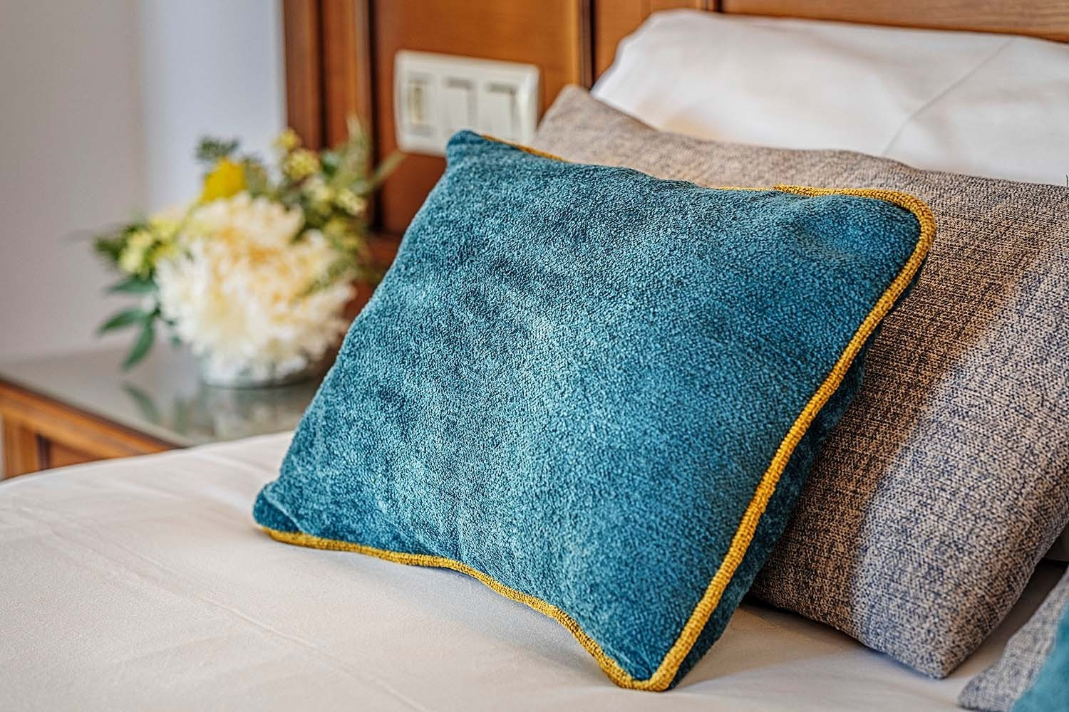 Cozy blue accent pillow on a bed at Rooms | Frigiliana Hotel | Beneste Hotels | Official Website.