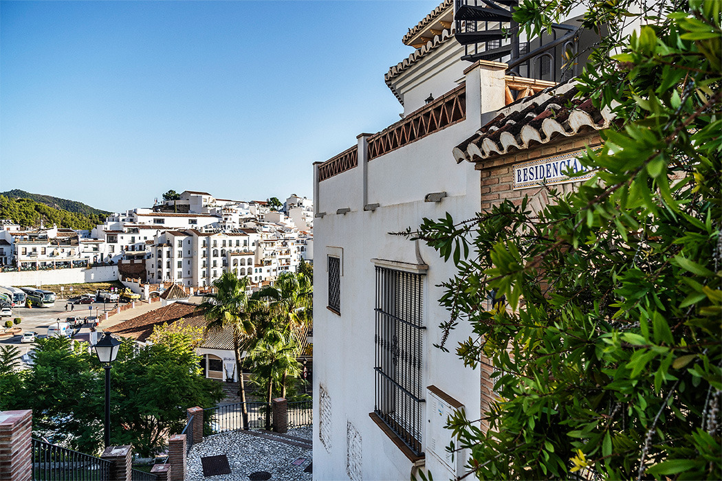 Vista de pueblo blanco español con BENESTE: Corporativa, arquitectura tradicional y vegetación frondosa.