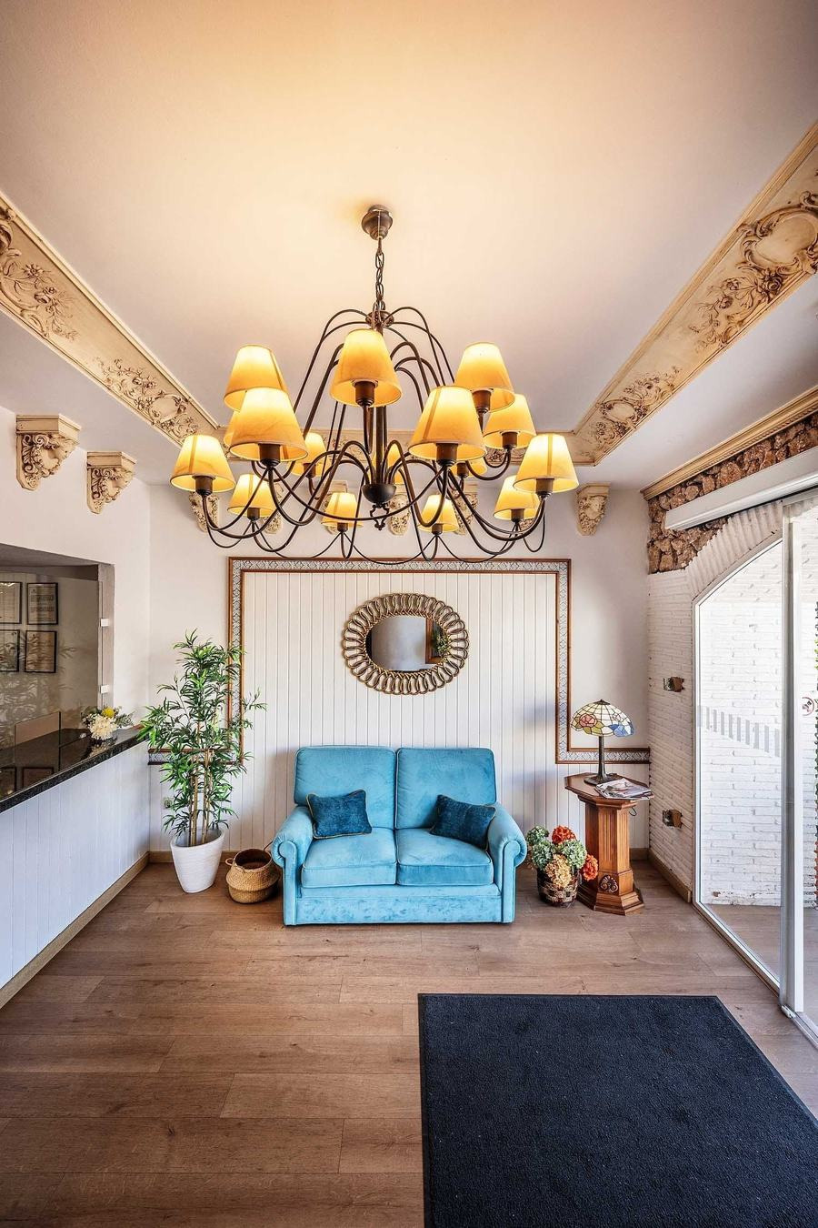 Cozy lobby with blue sofa, ornate chandelier & Frigiliana Hotel | Beneste Hotels | Official website signage.