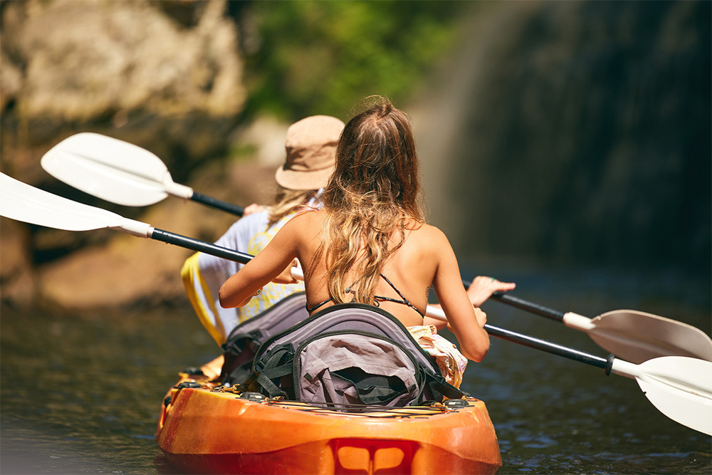 Dos mujeres en kayak disfrutando de la naturaleza BENESTE: Corporativa.