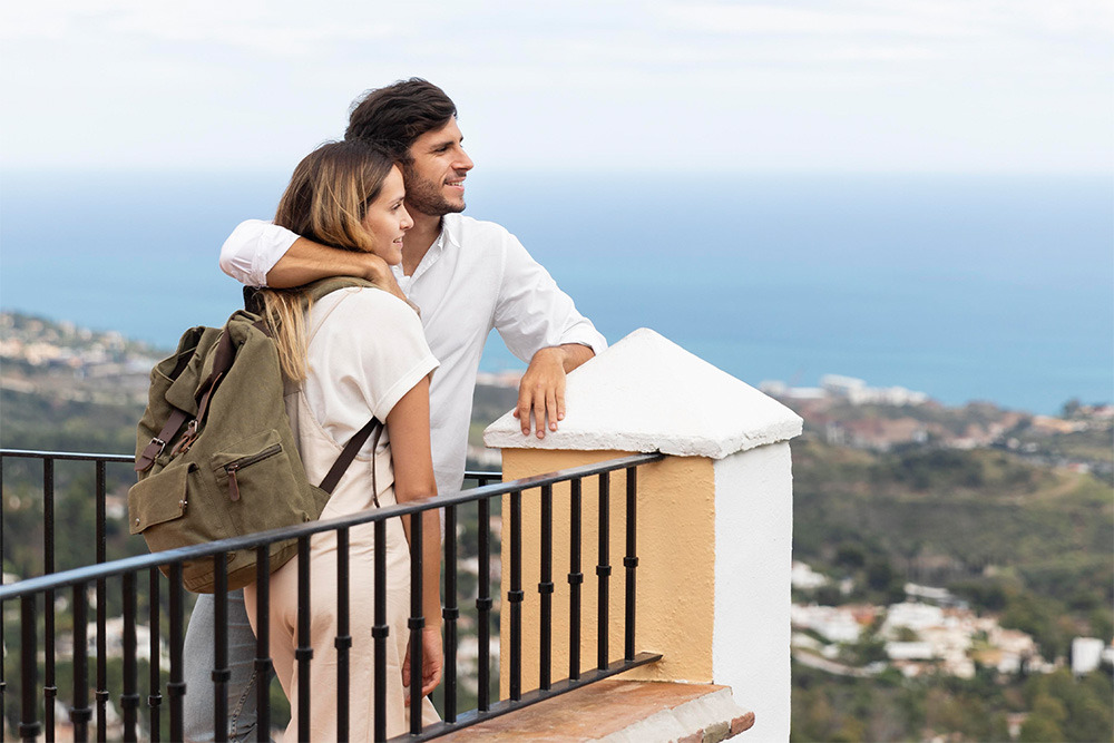 Pareja joven disfrutando de las vistas panorámicas desde la terraza de un hotel. BENESTE: Corporativa
