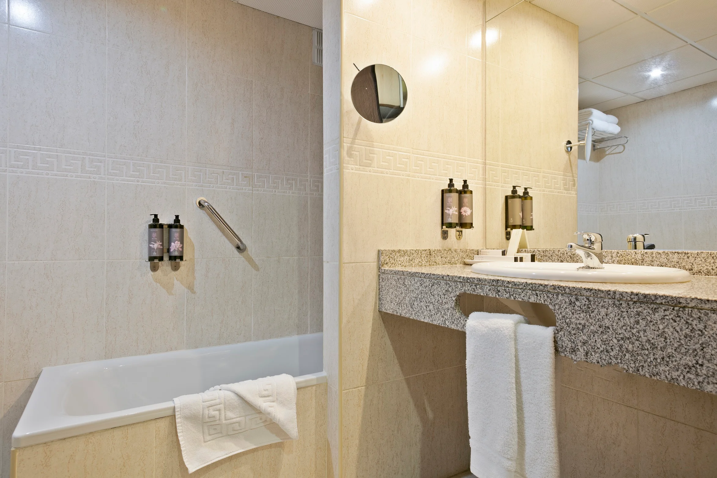 Baño moderno con bañera, lavabo con espejo y toallas limpias. Best Andorra Center