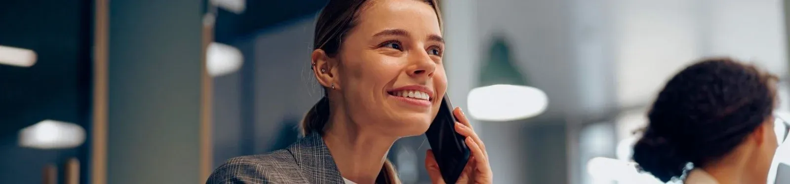 Mujer sonriente hablando por teléfono en el hotel, con detalles del interior. Best Corporativa