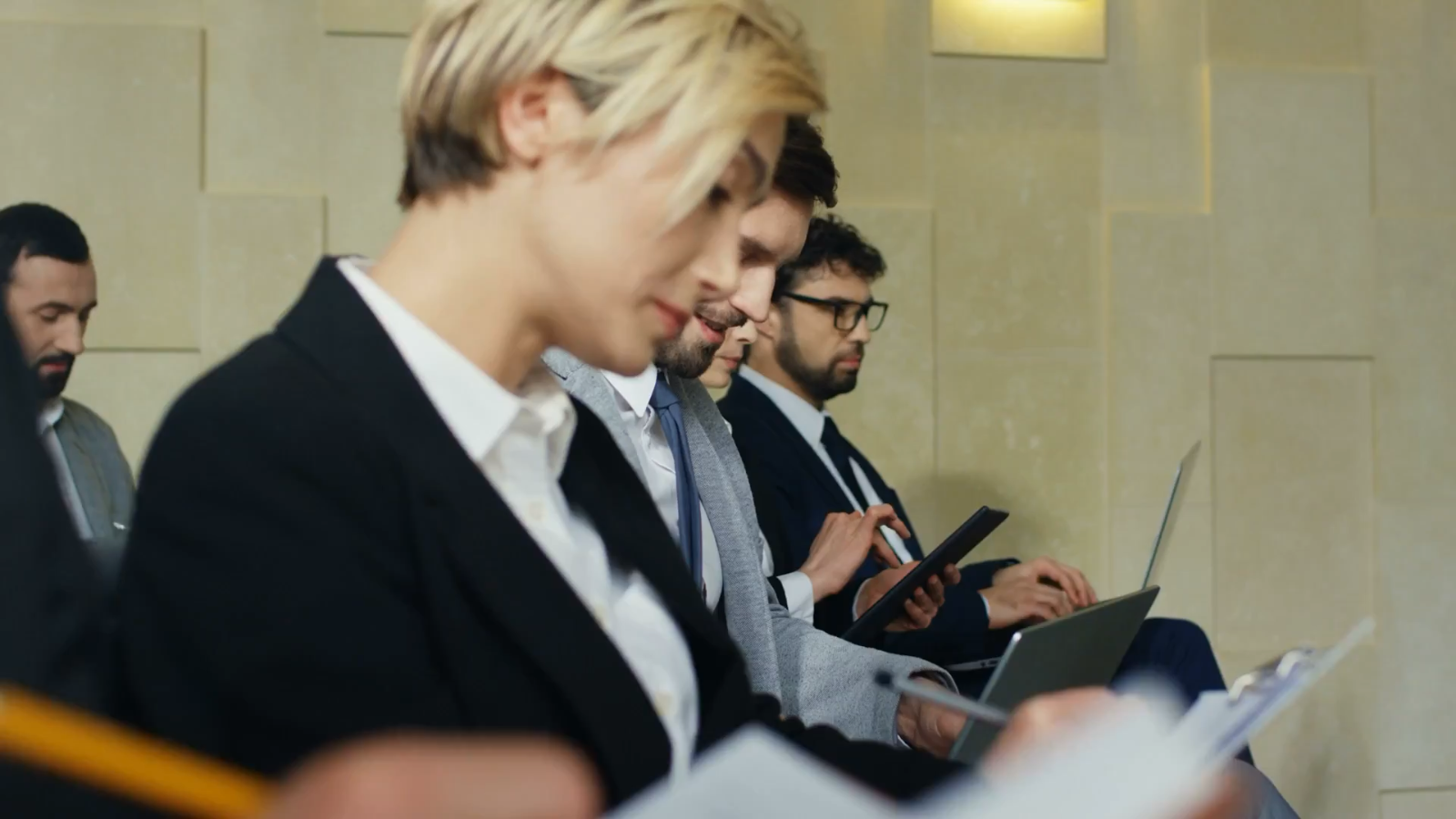 a group of business people are sitting in a row looking at their phones