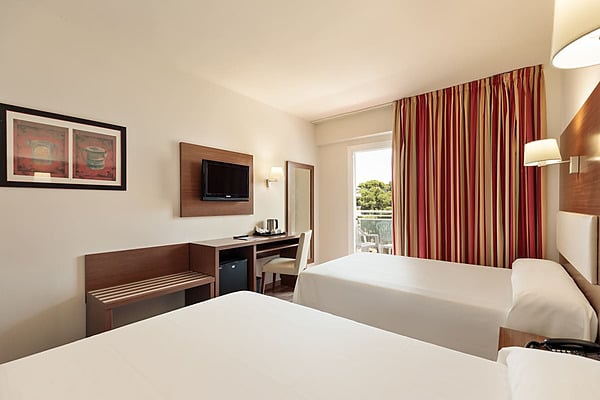 Doppelzimmer mit roten karierten Bettdecken, Balkonblick und einem Sofa Best Oasis Park, Salou | Offizielle Website | Bester Preis