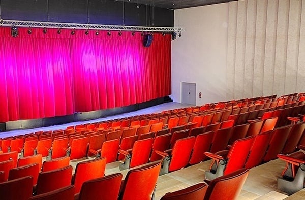 un auditorio lleno de asientos rojos y una cortina roja