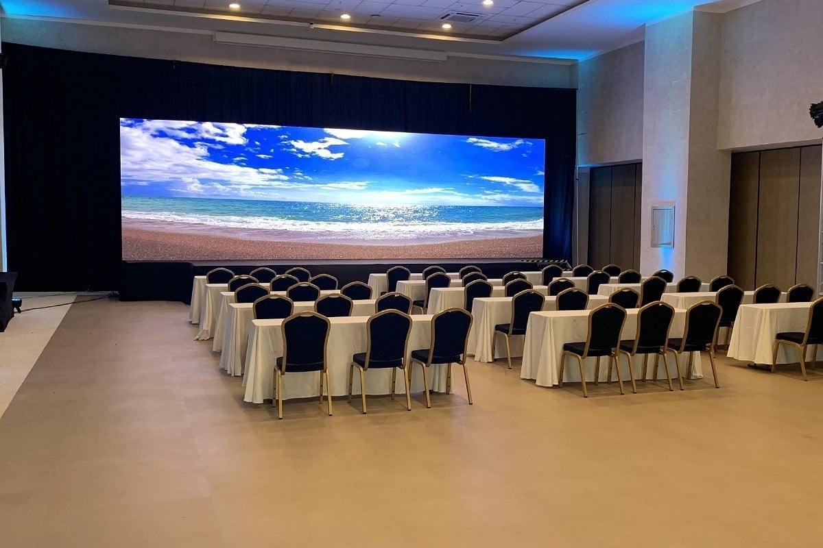 una sala de conferencias con mesas y sillas y una gran pantalla