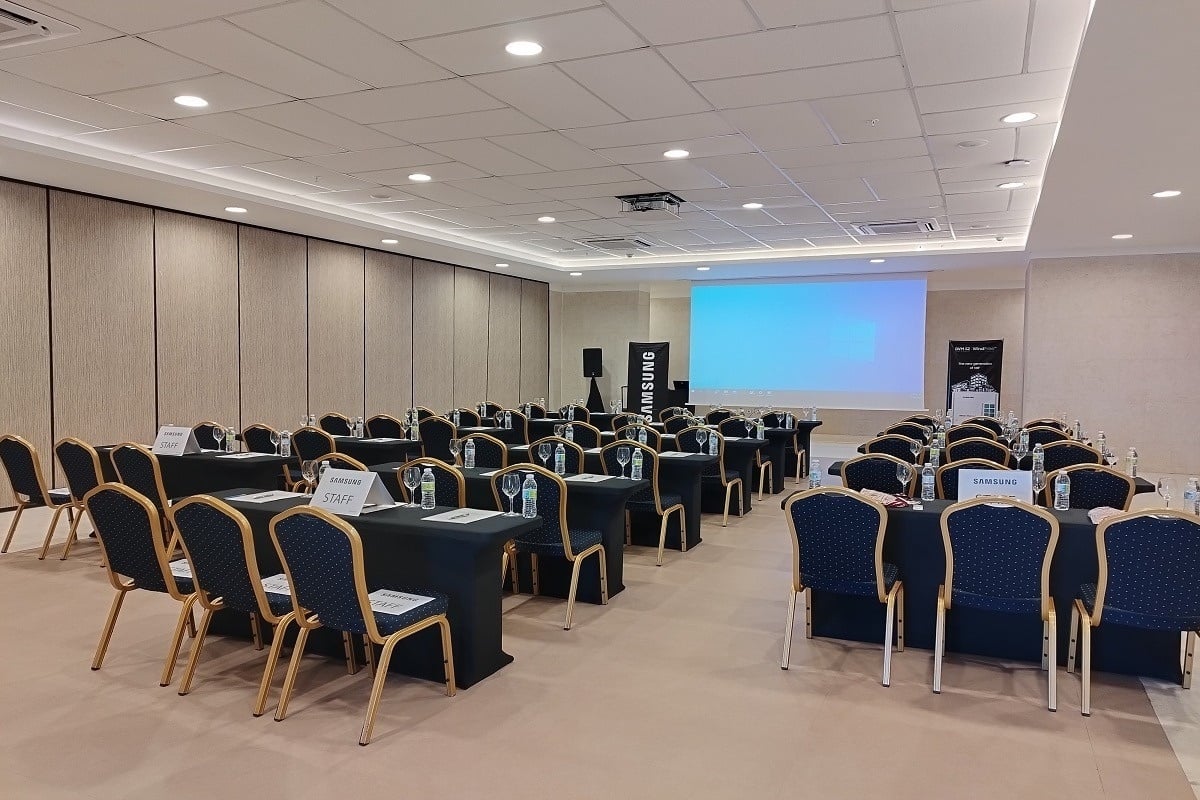 una sala de conferencias con mesas y sillas y una pantalla samsung