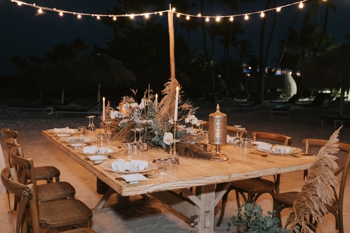 una mesa de madera con velas y platos en la playa