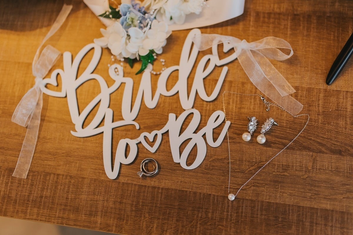 un signo de madera que dice " novia para ser " junto a un collar y aretes