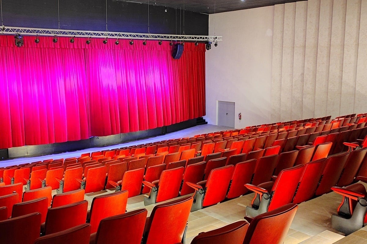 un auditorio vacío con cortinas rojas y asientos rojos