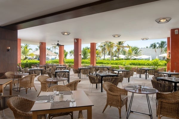a restaurant with wicker chairs and tables with a view of the ocean