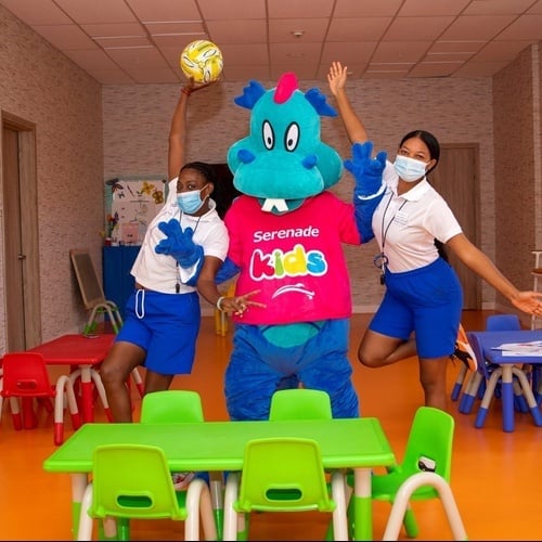 две женщины стоят рядом с талисманом serenade kids