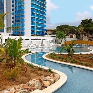 una piscina rodeada de plantas y árboles con un edificio en el fondo