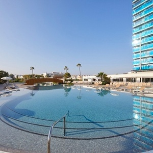 una gran piscina rodeada de sillas y palmeras