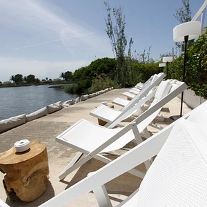 a row of white folding chairs are lined up near a body of water