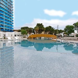 una piscina con un puente de madera y un edificio en el fondo