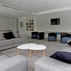ein Wohnzimmer mit grauen Möbeln und weißen Tischen