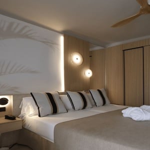 una habitación de hotel con una cama grande, luces led y batas de baño