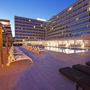 ein großes Hotel mit einem Pool und Liegestühlen davor