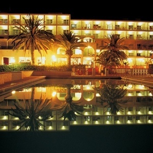 una piscina frente a un gran edificio iluminado por la noche
