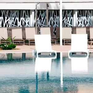 dos tumbonas blancas están junto a una piscina