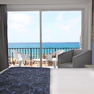 ein Hotelzimmer mit einem Bett und einem Balkon mit Blick auf das Meer